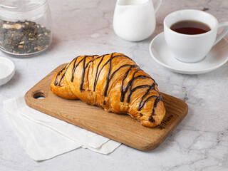 Fresh french chocolate croissant on wooden cutting board. Freshly backed croissants for breakfast.