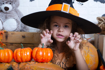 Funny child girl in witch costume for Halloween with pumpkin