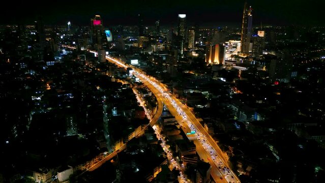 4K Cinematic urban drone footage of an aerial view of buildings and skyscrapers in the middle of downtown Bangkok, Thailand at night.