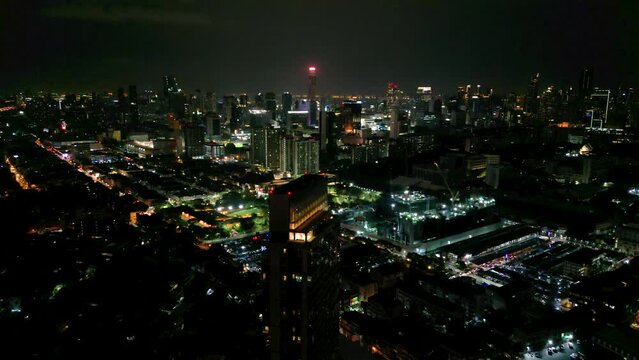 4K Cinematic urban drone footage of an aerial view of buildings and skyscrapers in the middle of downtown Bangkok, Thailand at night.