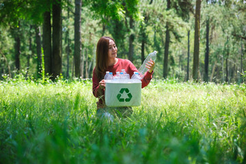 Portrait of a beautiful asian woman collecting garbage plastic bottles into a recycle bin in the...
