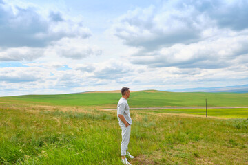 A man in light-colored clothes stands on the cliff of a hill and looks towards the Buryat Selenga River near the city of Ulan-Ude