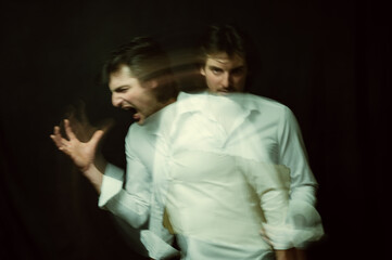 schizophrenic portrait of psychopathic man with mental disorders in white shirt on dark background
