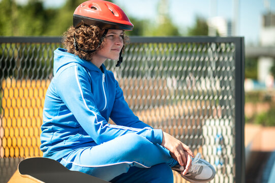 Calm dreamy adolescent skateboarder sitting alone outdoors