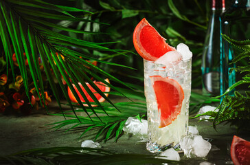Gin bitter grapefruit long drink cocktail with dry gin, tonic, and ice. Deep green background with...