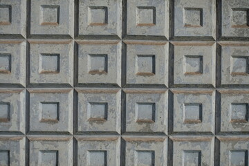 Surface of old dusty light grey concrete fence with embossed pattern
