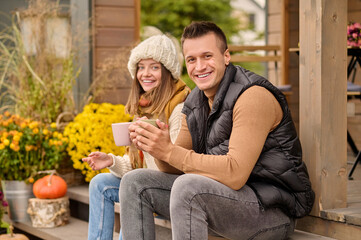 Fototapeta premium Cheerful young couple seated on the veranda