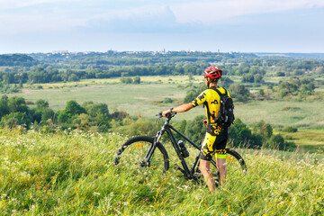 Fototapeta na wymiar A cyclist in sportswear poses with his mountain bike