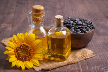 Closeup photo of sunflower oil with seeds on wooden background. Bio and organic product concept.
