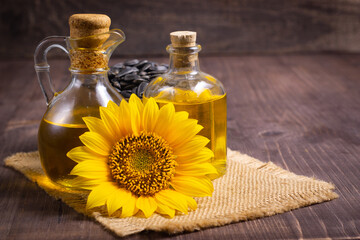 Closeup photo of sunflower oil with seeds on wooden background. Bio and organic product concept.