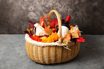 Fototapeta na wymiar Bottle of red wine with apples and cookies in a gift basket. Hamper for autumn Thanksgiving festival