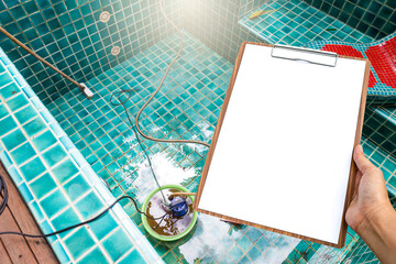 Blank wooden clipboard in girl hand over spa pool background, Swimming pool cleaning in rainy...