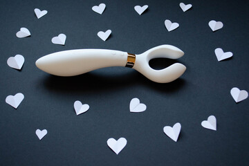 White vibrator on black dackground. White hearts. Sex shop assortiment