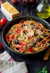 Spaghetti pasta Alla Puttanesca with capers, Kalamata olives, cheese, tomatoes and anchovies. Italian food.