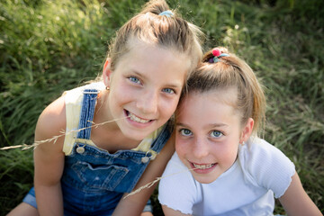 Fototapeta na wymiar two pretty young girls sisters friends have fun outside in a meadow in summer and are happy