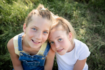Fototapeta na wymiar two pretty young girls sisters friends have fun outside in a meadow in summer and are happy