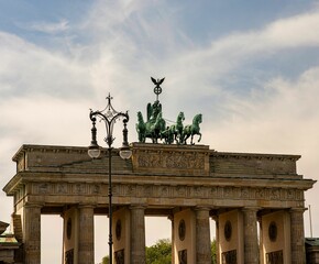 Low-angle view of Brandenburg Gate under the cloudy sky in Berlin