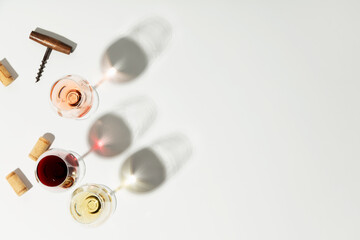 Flat-lay of red, rose and white wine in glasses on white background, copy space
