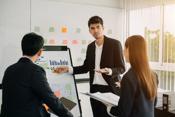 The boss stands near the board with graphs, demonstrates statistics, various personnel attending the training, introduces the new products of the company, in office