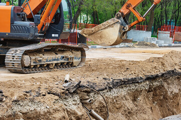 Reconstruction of an underground sewerage system on a city street in spring. The excavator digs a...
