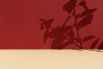 Premium podium with a shadow of plant leaves on a red wall and a beige table. Minimal abstract...