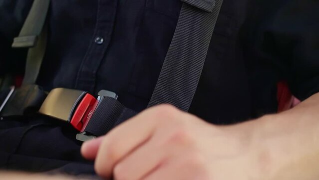 Pilot of the airplane puts on his seat belt.Man sitting in the plane closes his seat belt.Hands shot.
