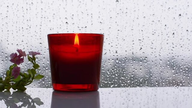 Burning aroma candle puts near by window with small tree and flowers that have rain drop in monsoon season. Zen and relax concept.