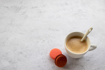 Cup of coffee cappuccino, latte and colorful macarons dessert on white table background. Morning weekend sunday coffee. Top view, flat lay, copy space