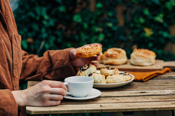 Woman drink a coffee and eats french cookies on table in garden