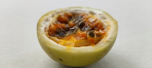 Half slice of ripe juicy organic yellow passion fruit, passiflora edulis or maracuya isolated on white table backghround with copy space. Passionfruit pulp natural antioxidant closeup macro side view.