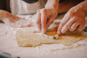 Closeup view on hands how mother with son preparing flour for cookies in the kitchen