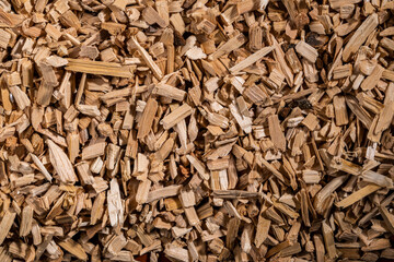 Background of brown dry wood splinter. Wooden chips and slivers. Crushed, chopped wood tree for burning in kiln in winter. Biofuel, lumber. Wooden material. Small pieces of firewood close up. Top view