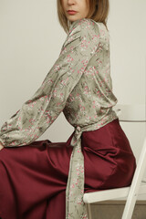 Serie of studio photos of young female model silk satin floral blouse with simple burgundy midi...