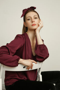 Serie of studio photos portrait of young female model in silk satin burgundy blouse