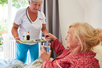 Altenpflegerin bringt Medikamente ans Bett von Seniorin