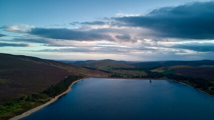 Obraz premium a colourful sky and an aerial picture of a water reservoir at dusk.