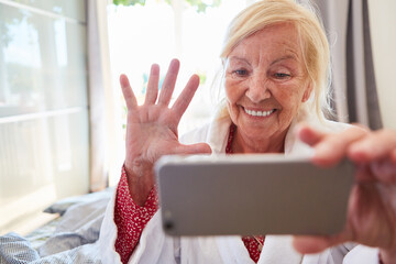 Seniorin freut sich über einen Video Call am Smartphone
