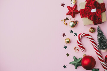 Stylish christmas border with festive decorations, confetti, trees flat lay on pink background. Merry Christmas and Happy Holidays! Creative seasons greeting card, space for text