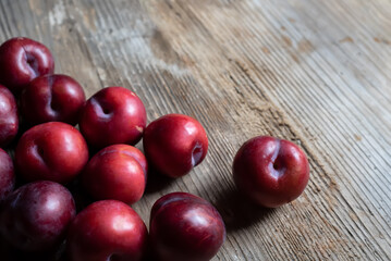 Group of ripe plums on rustic wood with copy space