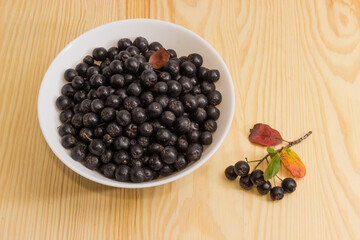 Chokeberry in the white bowl on a wooden surface