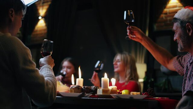 Groups of people celebrate Christmas eve and have dinner at night which have many food and wine on the table.