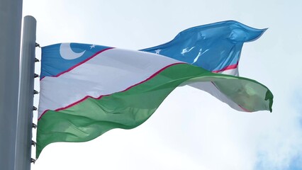 Uzbekistan, flag is fluttering in the wind photo on the background of the sky, outdoors. National...