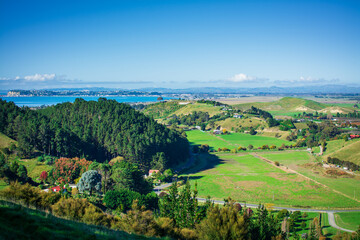 Majestic view over farmhouse amongst lush meadows by green hills. Beautiful autumn day at a seaside region of Hawkes Bay, New Zealand