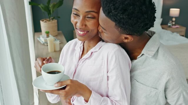 Happy couple, morning coffee and hug to show love and care while looking out hotel, apartment or bedroom window on honeymoon vacation. Happy black man and woman showing commitment and romance