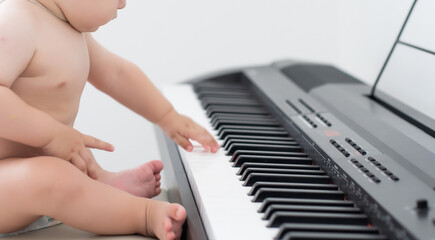 Fototapeta premium toddler baby boy, playing piano at home, child learning