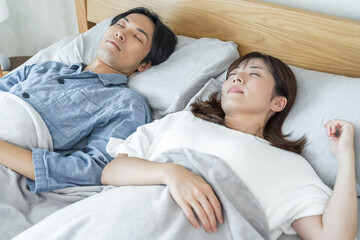 寝室のベッドで一緒に寝る夫婦
