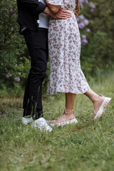 cropped photo of loving couple is hugging, walking and kissing in the lilac garden in spring day. Young woman in dress and man on a romantic date on nature. Love and relationship concept