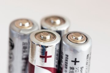 A close up portrait of the plus or positive side of a couple of triple A or AAA batteries standing upright.