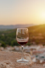 Close-up of a glass of red wine with a background of mountains with sunset light