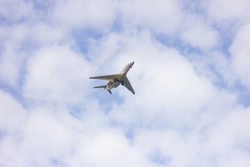 A portrait of a private plane flying low in a cloudy sky. The jet plane has started to descend for landing and landing gear is or the wheels are out.